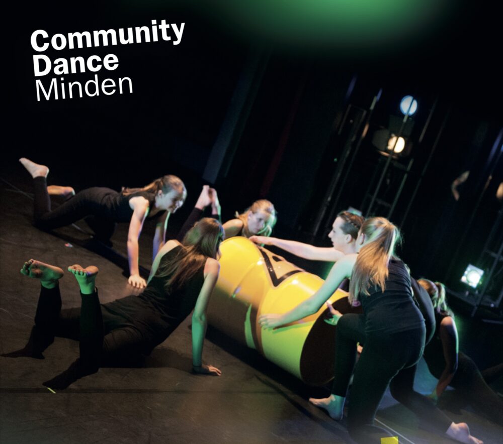 Mehrere schwarz gekleidete Schülerinnen greifen eine große gelbe Tonne mit einem Warnschild, die auf auf dem Boden liegt.