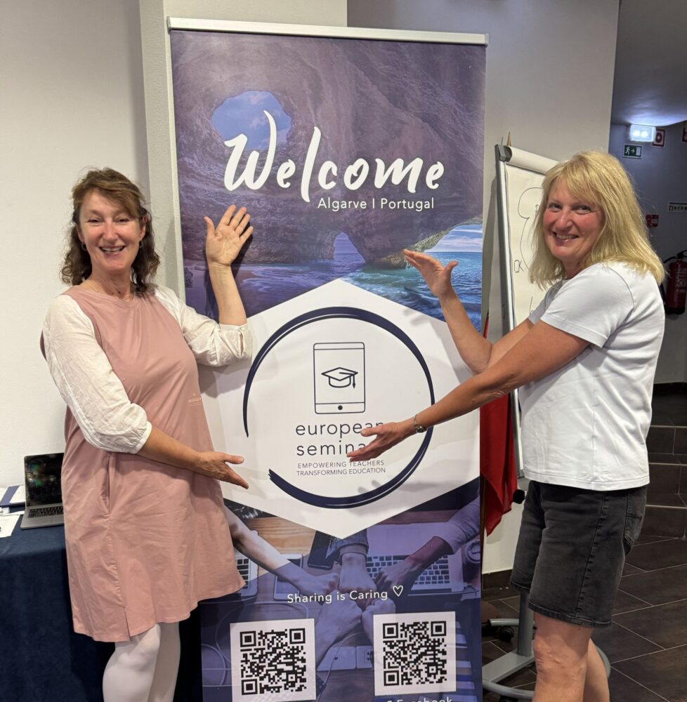 2 Lehrerinnen vor einem Wellcome-Roll up zum Erasmus+ Seminar
