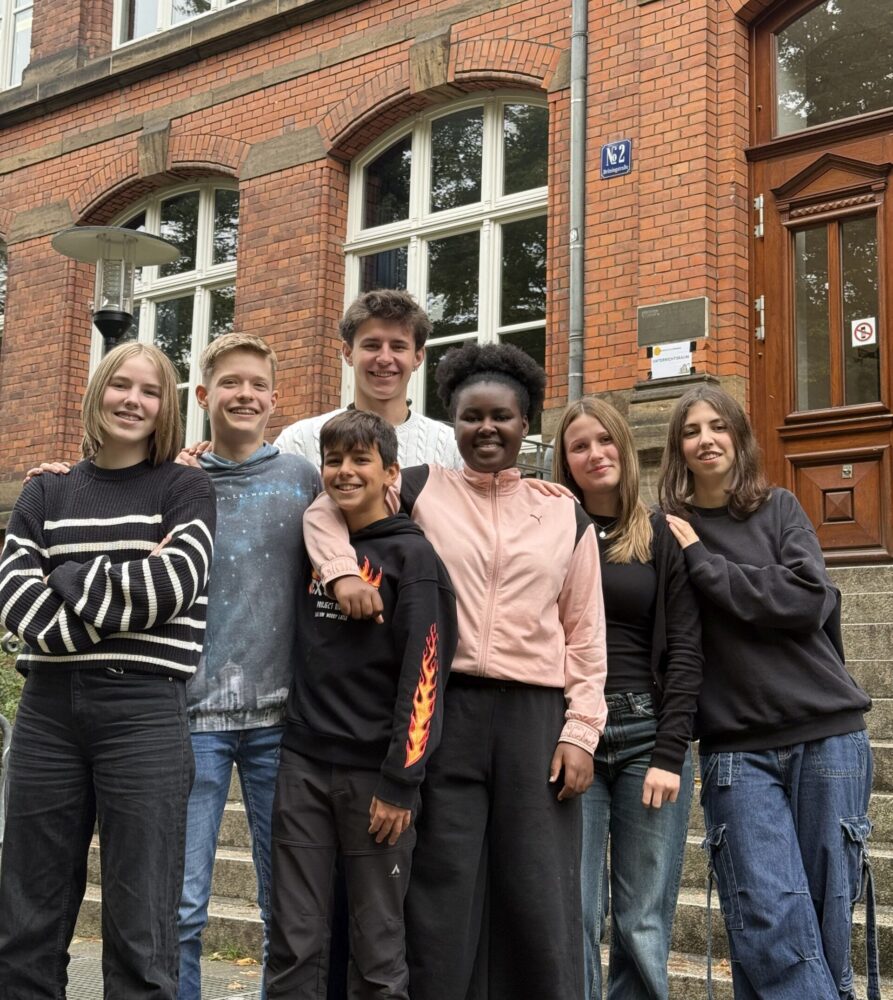 Schüler:innen vor der Treppe vor dem alten Haupteingang zum Herder-Gymnasium.