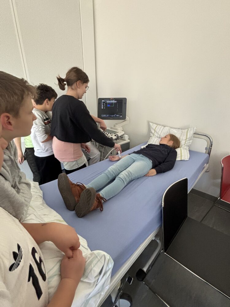 Schüler:innen untersuche eine Mitschülerin mit dem Ultraschallgerät.