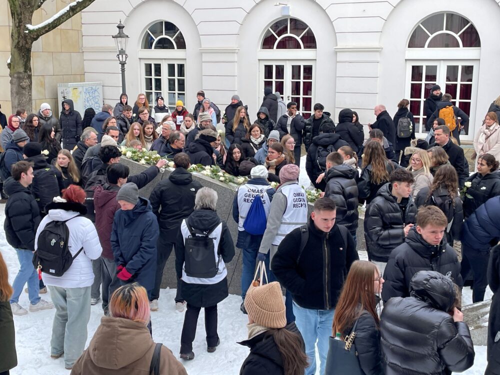 Schüler*innen und Bürger*innen legen Rosen und Steine am Mahnmal nieder