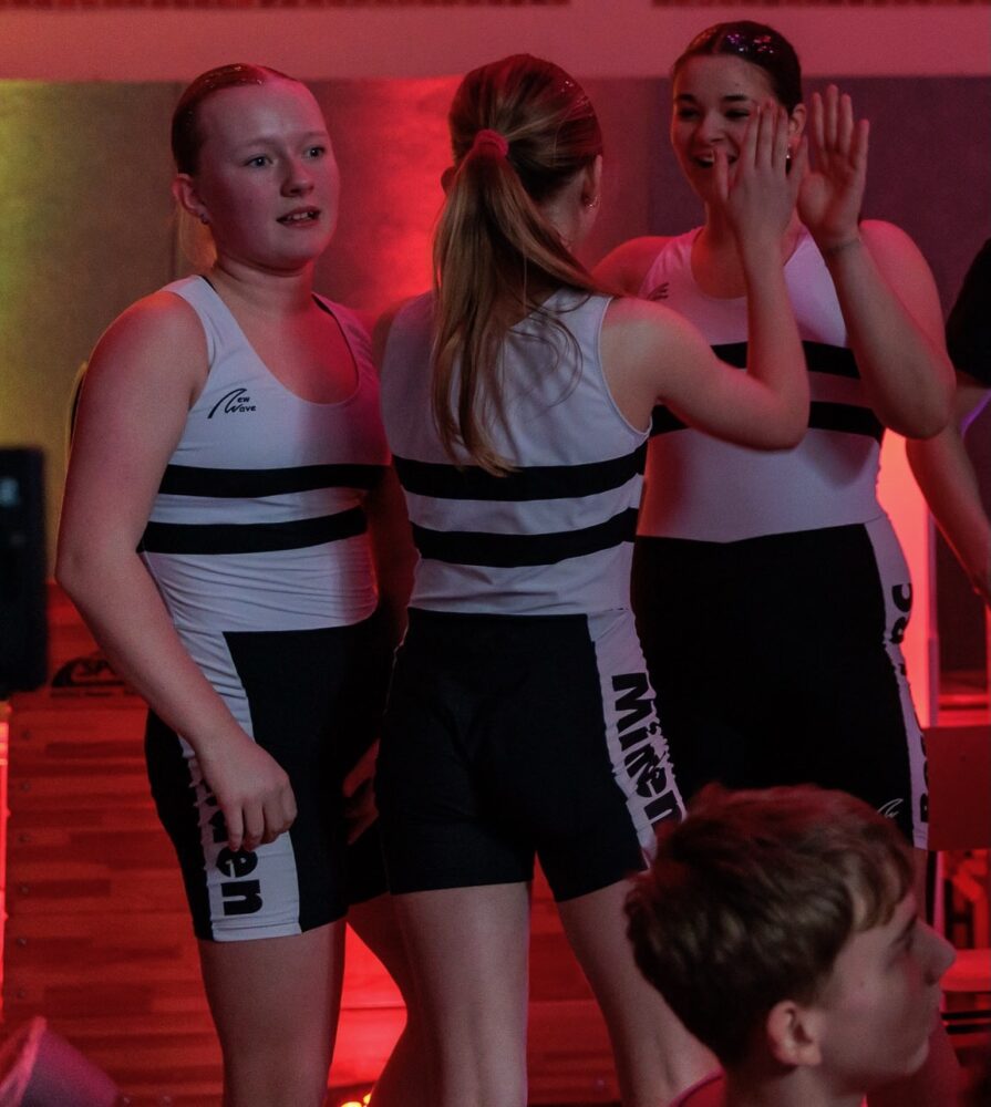 Drei junge Ruderinnen freuen sich und klatschen sich ab