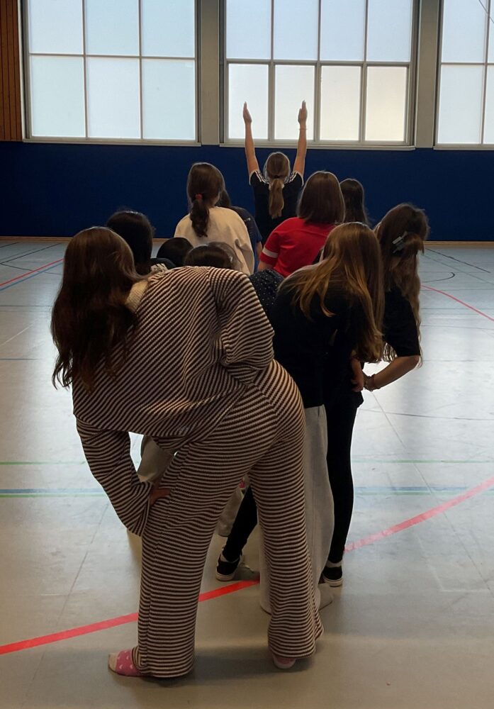 Die Tänzerinnen stehen hintereinander und drehen sich abwechselnd nach links und nach rechts.