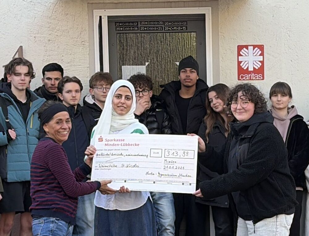 Schüler:innen mit dem Spendenscheck vor der Wärmestube St. Nikolai Minden