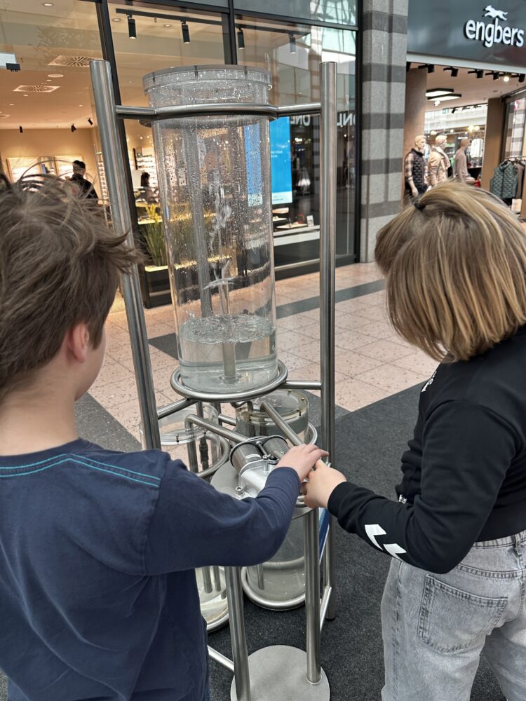 Wassersäule, die zwei Kinder interessiert betrachten