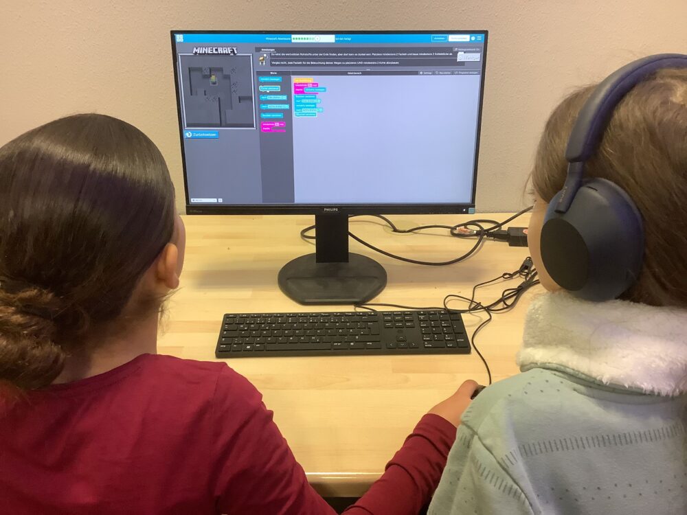 Zwei Schülerinnen sitzen am PC und programmieren